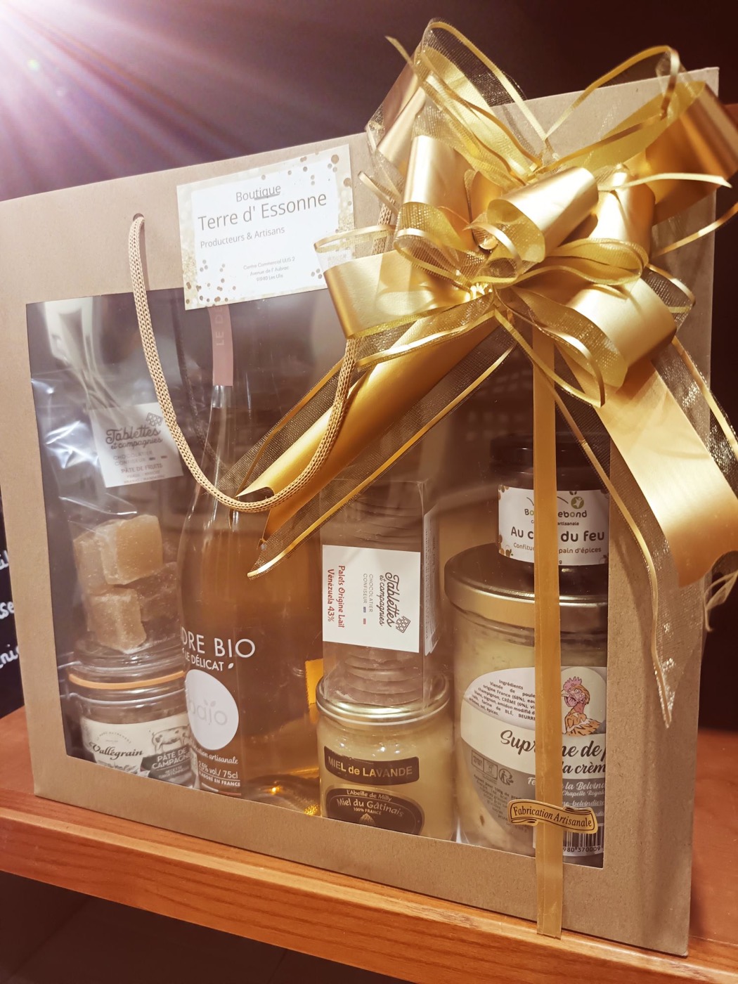 Coffret kraft Terre d’Essonne garni de miel du Gâtinais, cidre, pâtes de fruits et terrine, noué d’un ruban doré